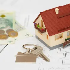 Model domu, klucze, pieniądze i plany architektoniczne.